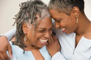 An adult daughter wrapping her arms around her smiling mom