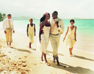 Newlywed Couple Walk Face-to-Face on a Beach, Accompanied by Bridesmaids and Best Man