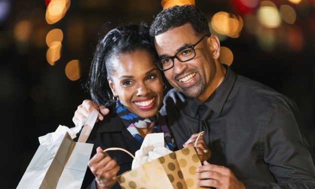 Happy black couple opening a gift bag outdoors at night