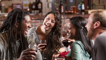 Multiracial group of friends drinking at restaurant bar