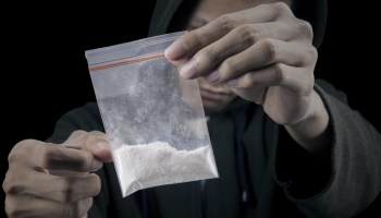 Drug dealer is preparing packet of heroin or cocaine