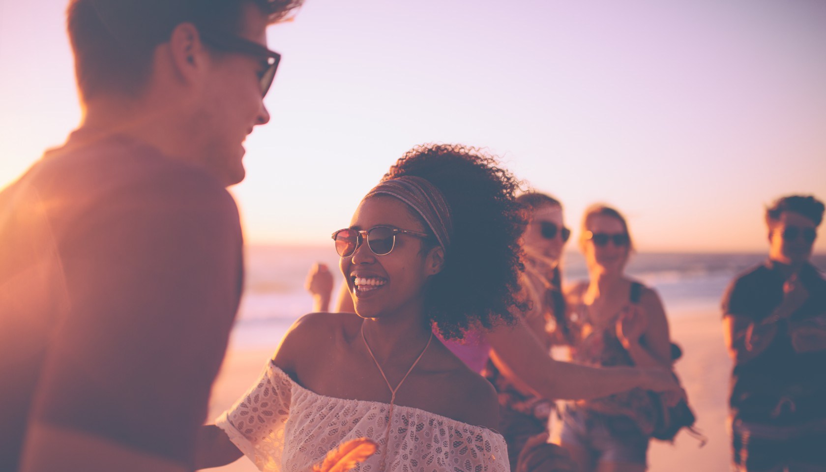 Afro girl dancing with her boyfriend at a sunset beachparty