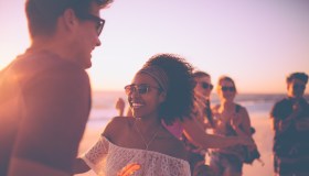 Afro girl dancing with her boyfriend at a sunset beachparty