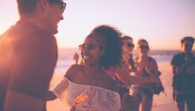 Afro girl dancing with her boyfriend at a sunset beachparty