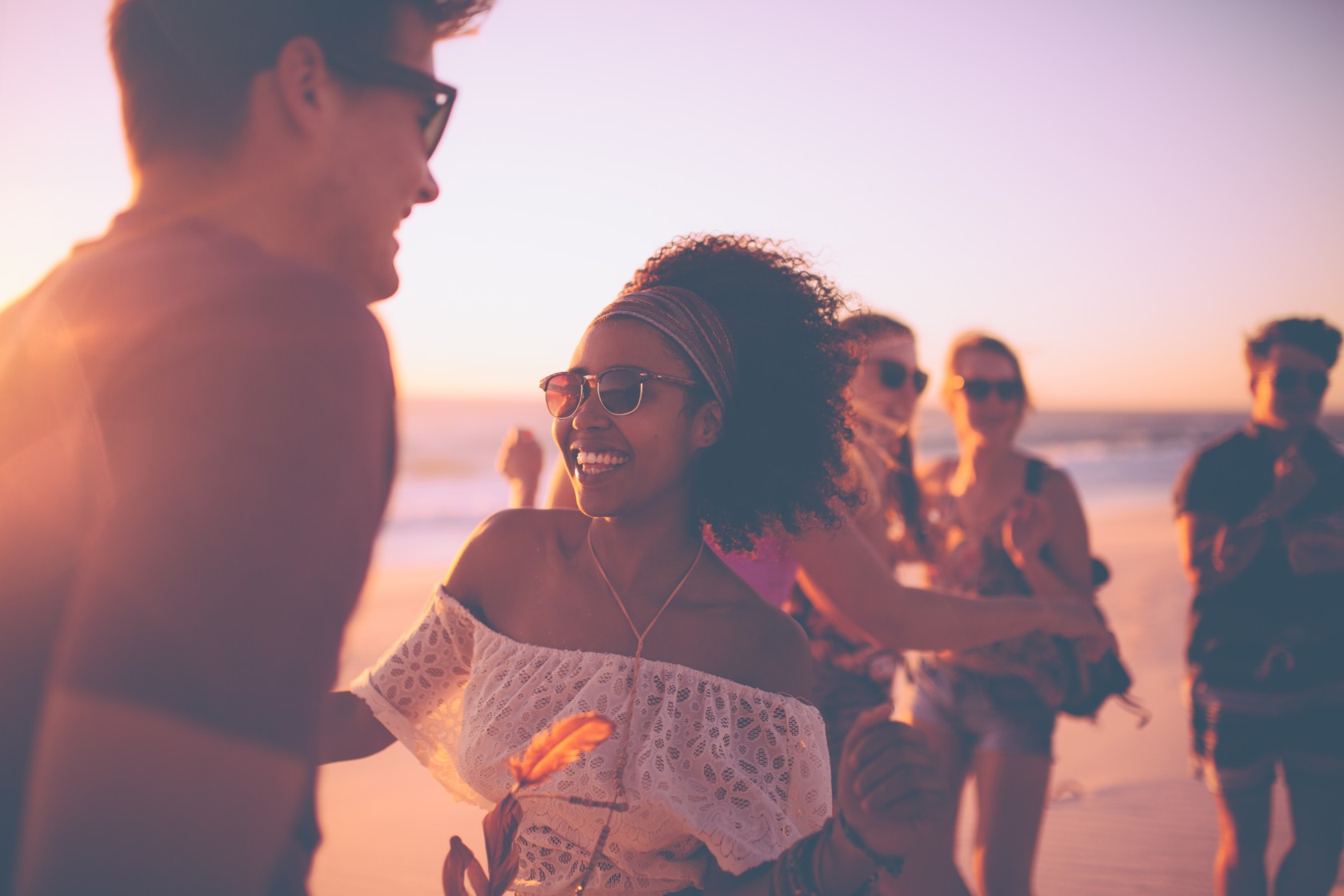 Afro girl dancing with her boyfriend at a sunset beachparty