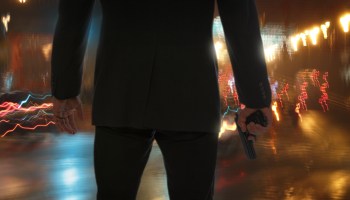 Bodyguard standing with gun during rain at night.