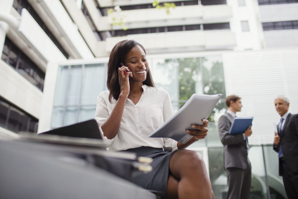 Businesswoman talking on cell phone looking at documents