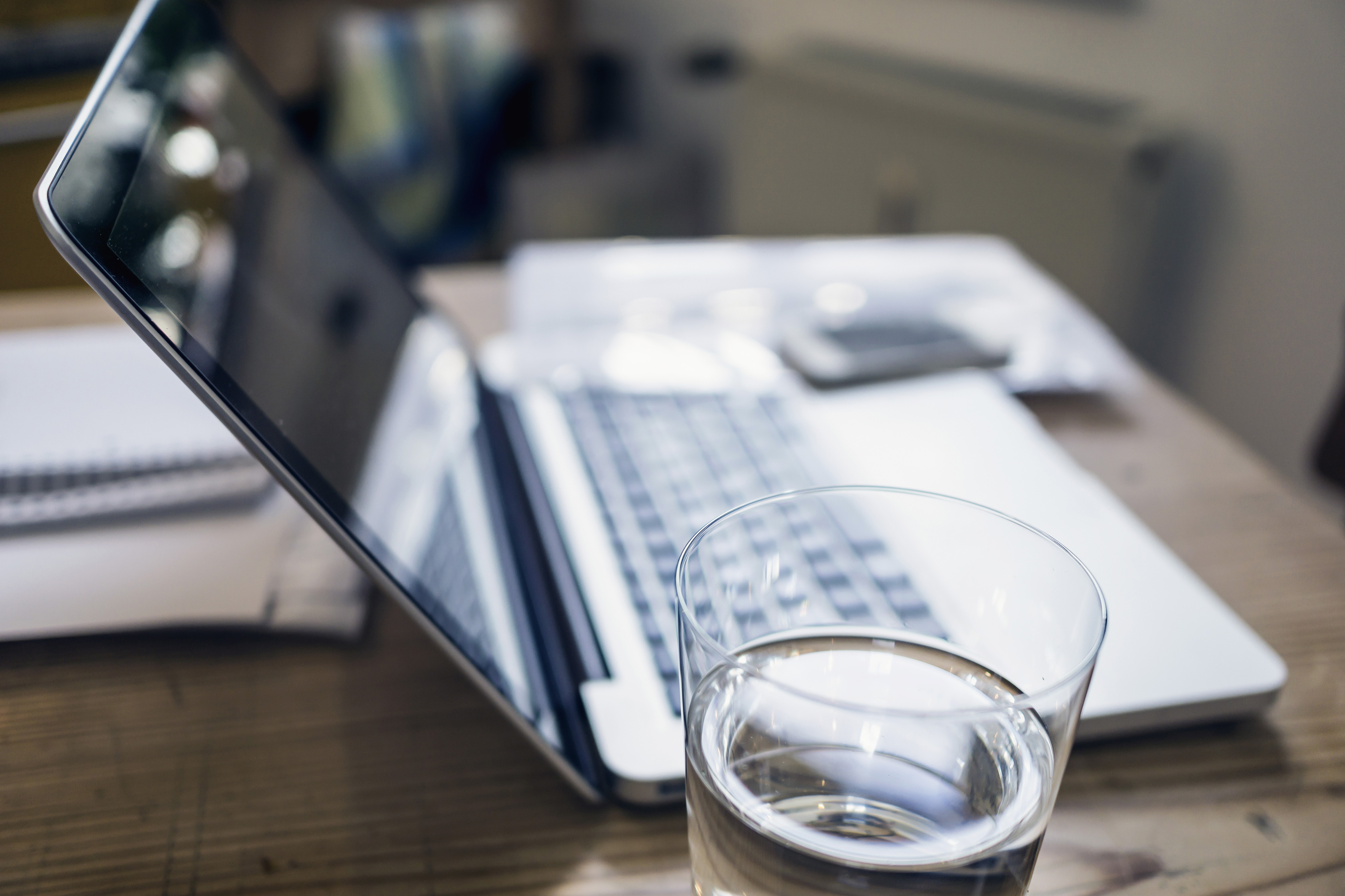 Glass of water, documents and laptop on a wooden table