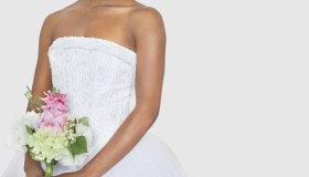 Midsection of bride holding bouquet over gray background