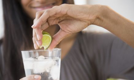 Mixed race woman squeezing lime into drink