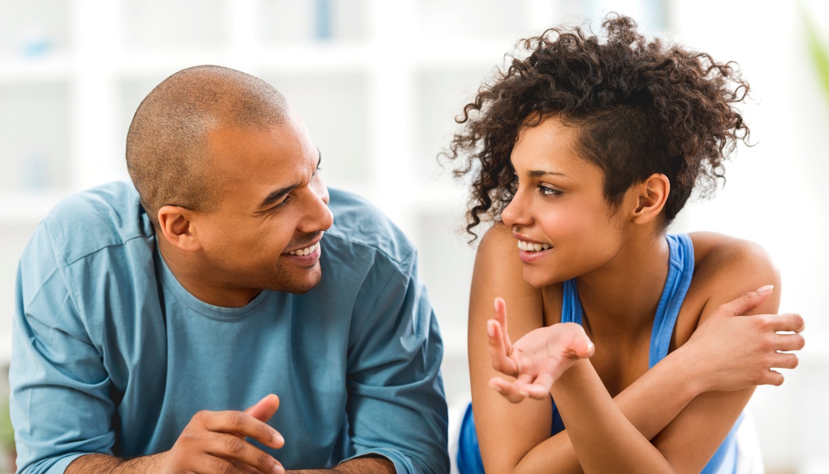 Smiling African American couple lying on carpet and communicating.