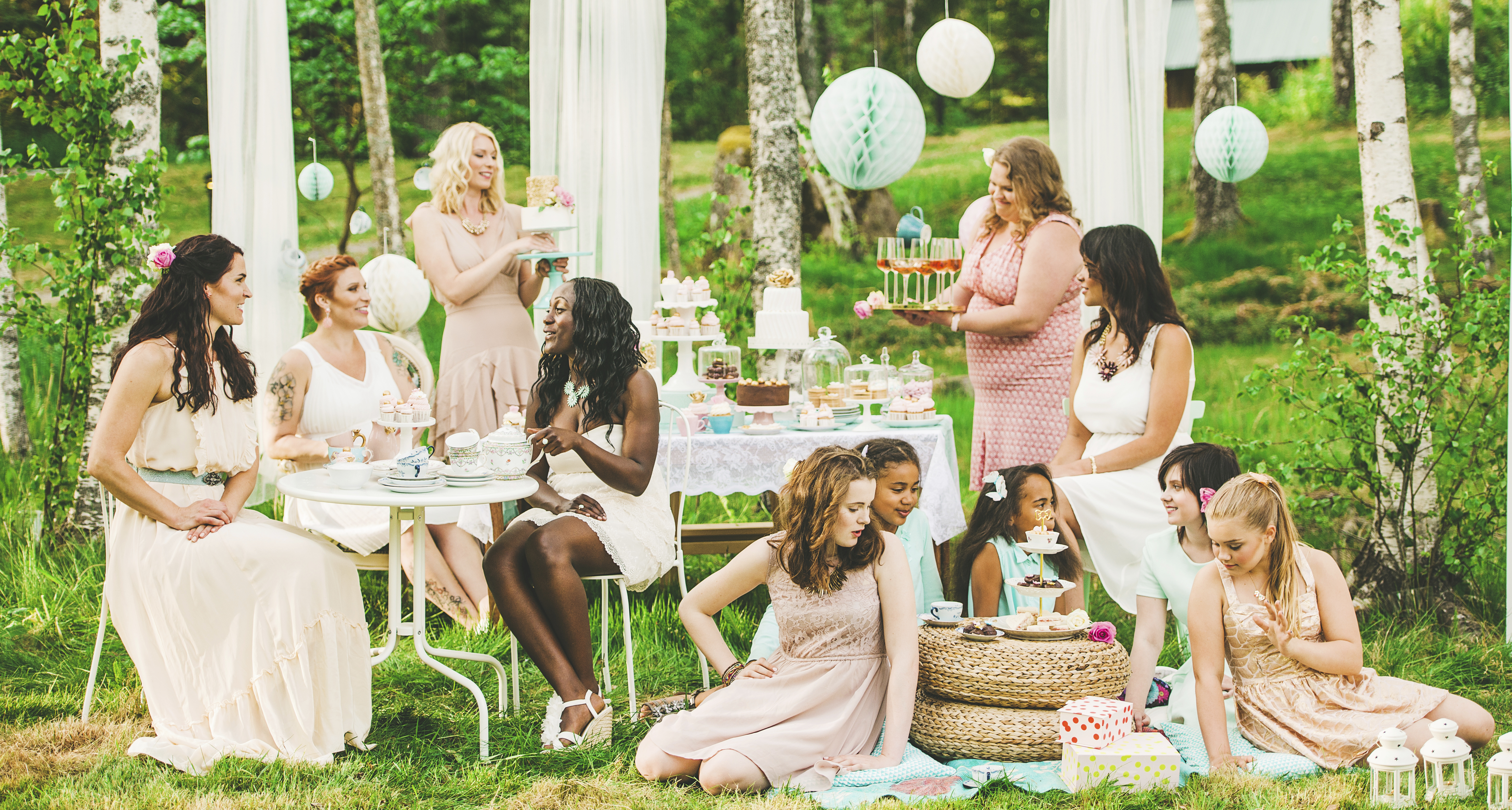 Eleven women having a garden party with dessert table