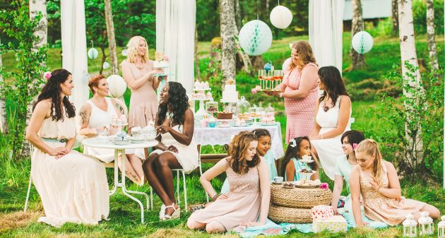Eleven women having a garden party with dessert table