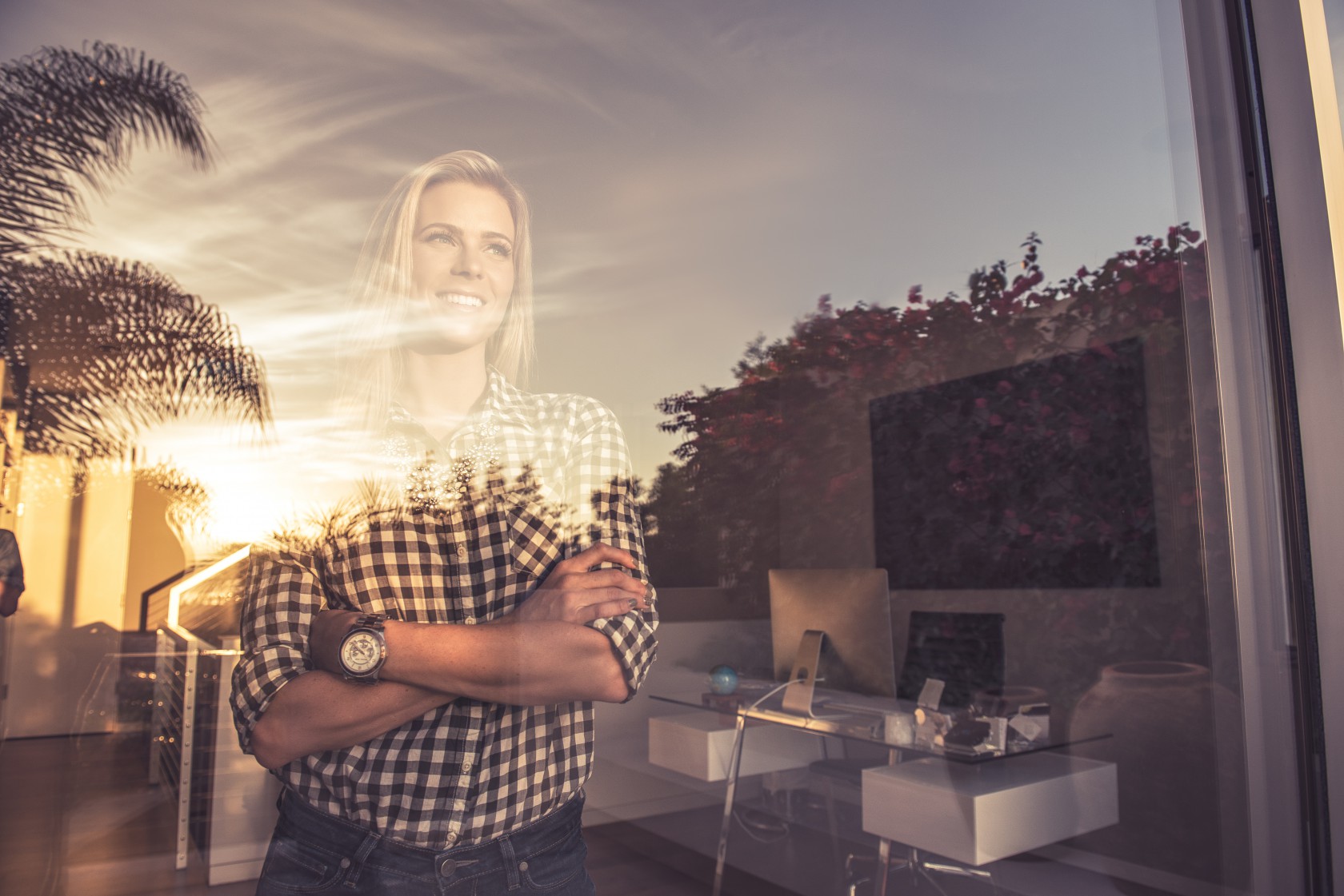 Portrait of young woman watching sunset from suburban window