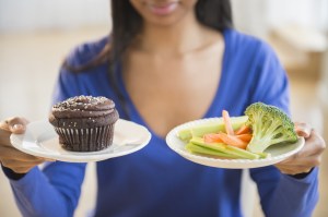 woman holding cupcake and veggies