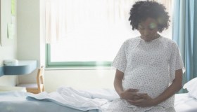 Pregnant African American woman holding her stomach in hospital