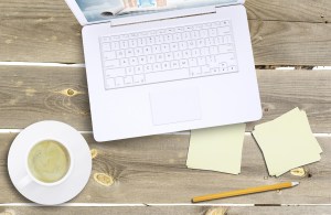 Laptop and coffee cup on old wooden boards. Computer technology concept