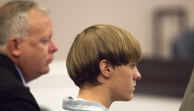 Dylann Roof (R), the 21-year-old man charged with murdering nine worshippers at a historic black church in Charleston last month, is helped to his chair by chief public defender Ashley Pennington during a hearing at the Judicial Center in Charleston