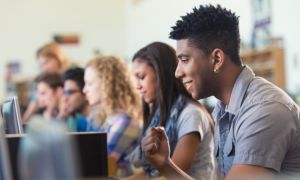 African American college student smiling while using computer in library