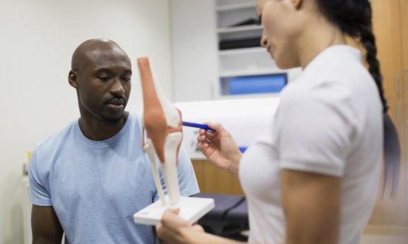 Physical therapist explaining knee model to patient