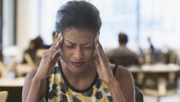 Anxious mixed race businesswoman rubbing temples in office
