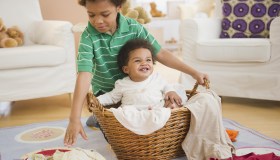 Black boy putting sister in laundry basket