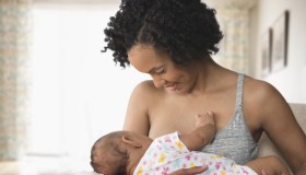 Mother breastfeeding baby in living room