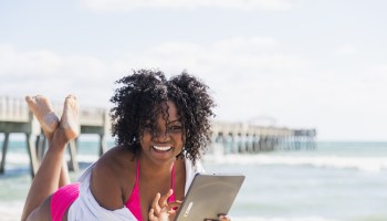 African American woman using digital tablet on beach