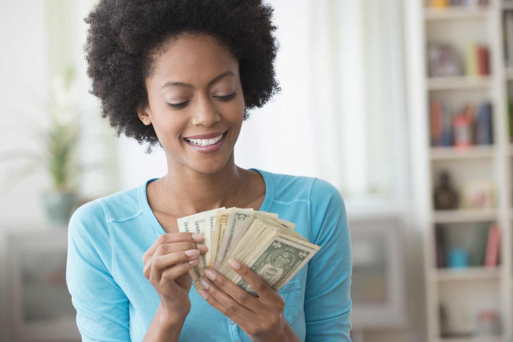 African American woman counting money in living room