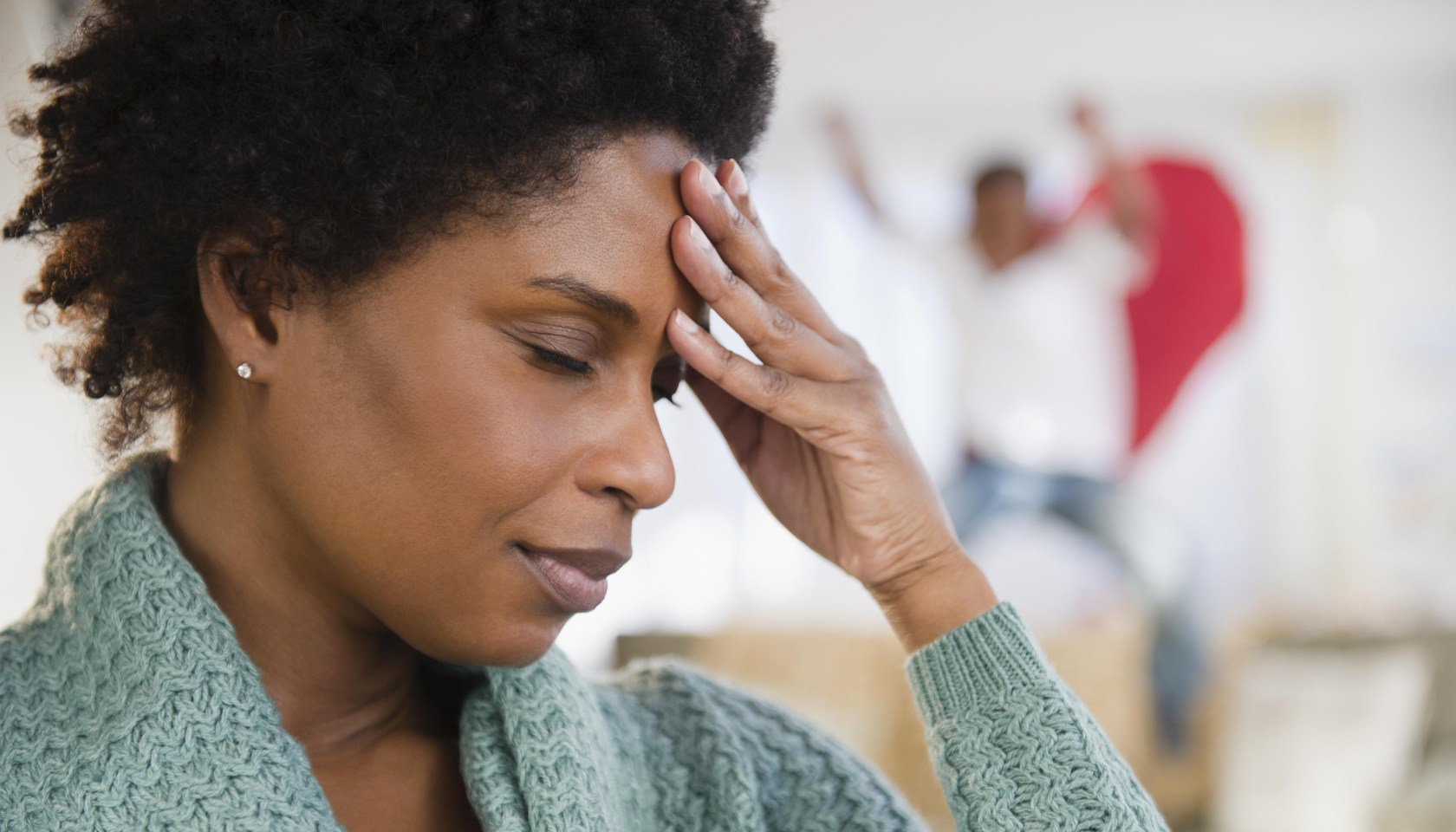 Black woman with headache and playful son in background