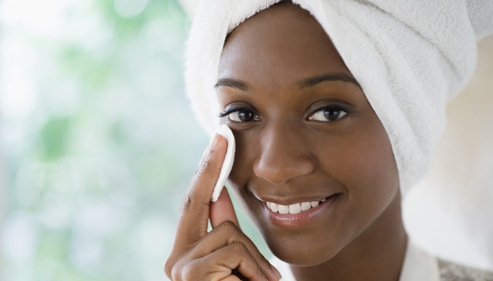 Black woman wiping face with cotton pad