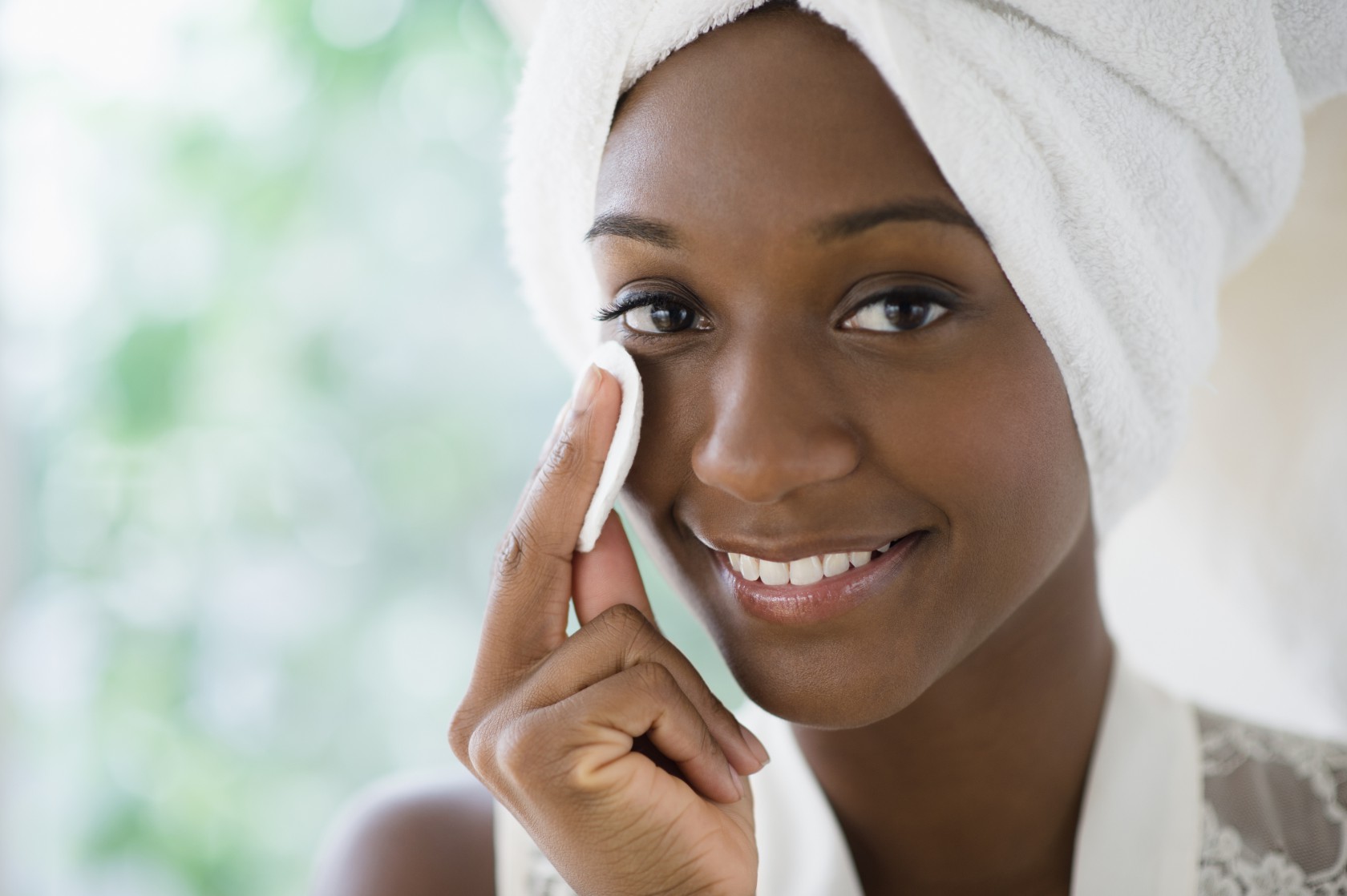 Black woman wiping face with cotton pad