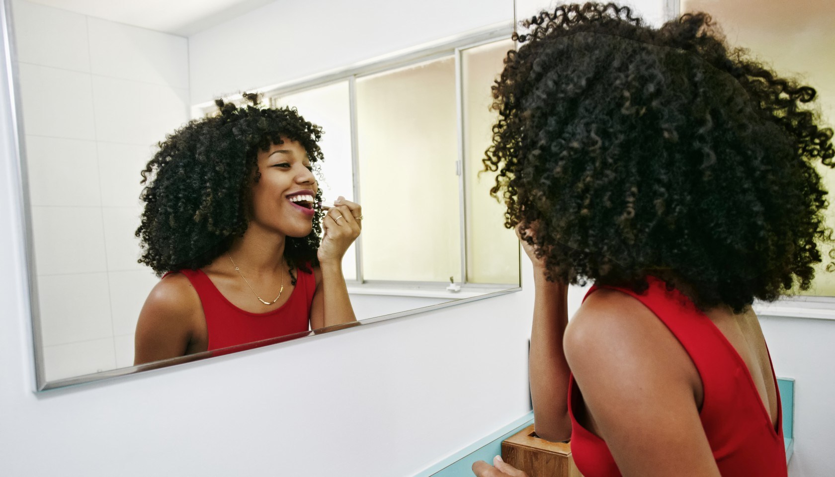 Mixed race woman applying makeup in mirror