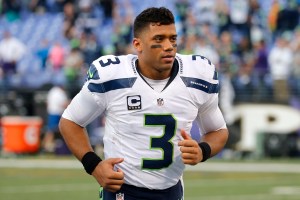 Seattle hip hop and rap singer Macklemore greets Seattle Seahawks  quarterback Russell Wilson before an NFL football game between the Seahawks  and Tennessee Titans, Sunday, Oct. 13, 2013, in Seattle. (AP Photo/Elaine