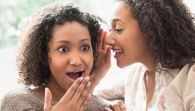 Surprised women whispering secrets