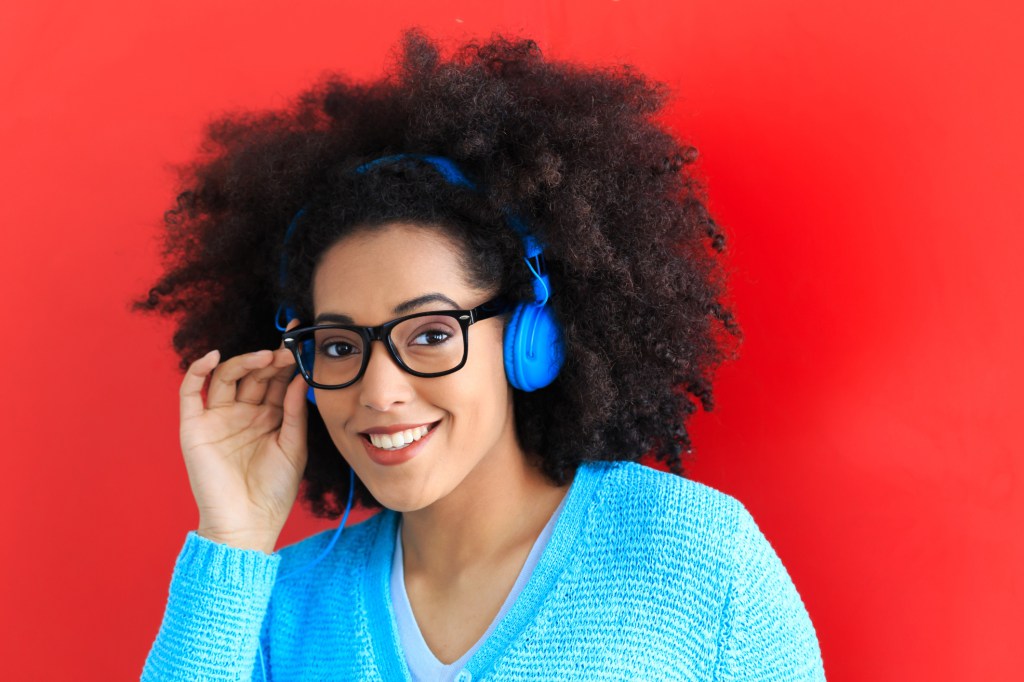 Young woman with blue headset and eyeglasses listening music