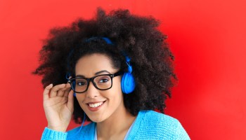 Young woman with blue headset and eyeglasses listening music