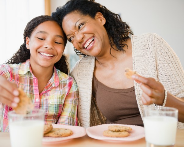 Mother and daughter eating cookies and milk together