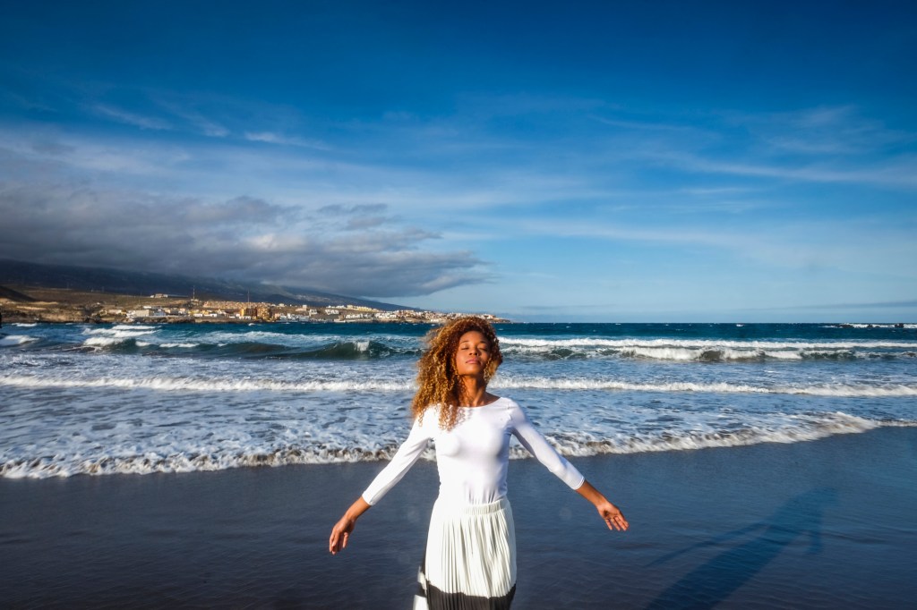 Spain, Tenerife, woman with closed eyes standing on the beach