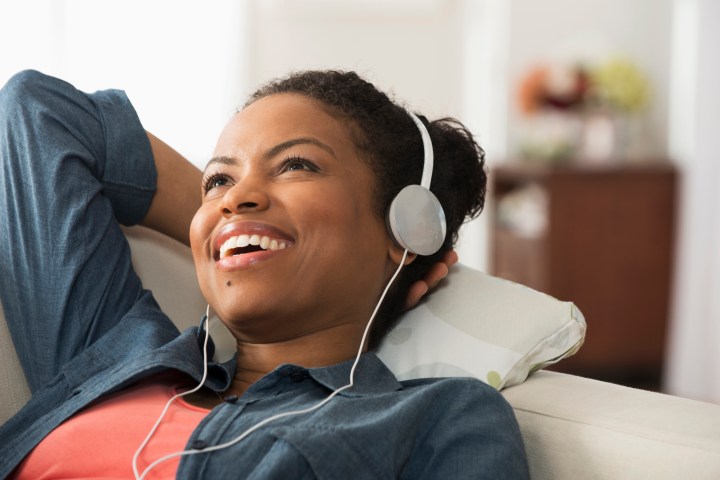 Mixed race woman listening to headphones on sofa