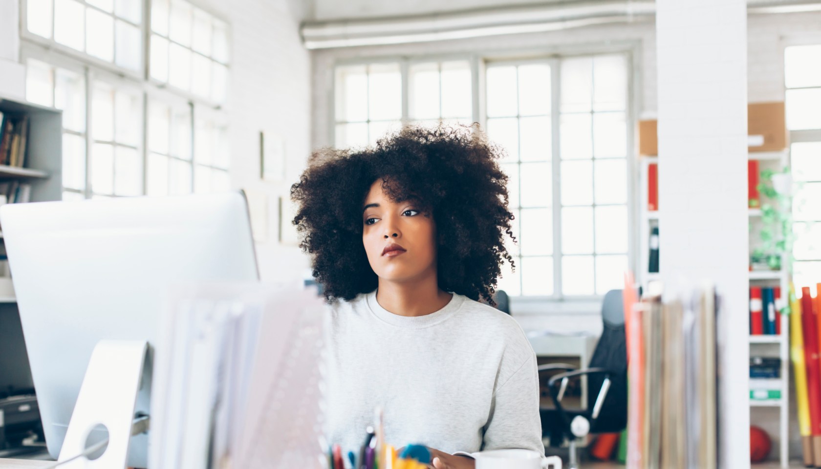 Depressed young woman using computer at the office