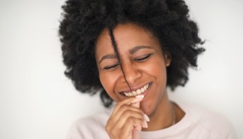 Smiling Black woman playing with hair