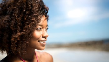 Close-up of thoughtful woman smiling at beach