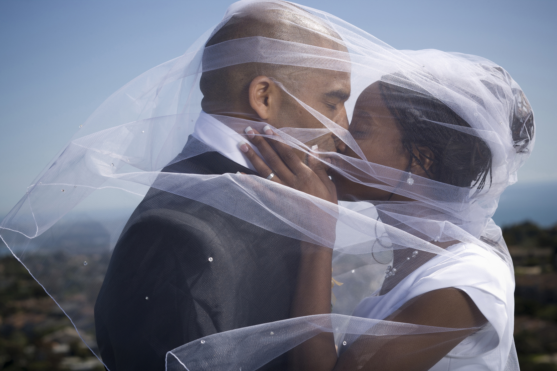 Profile of a newlywed couple kissing each other under a veil