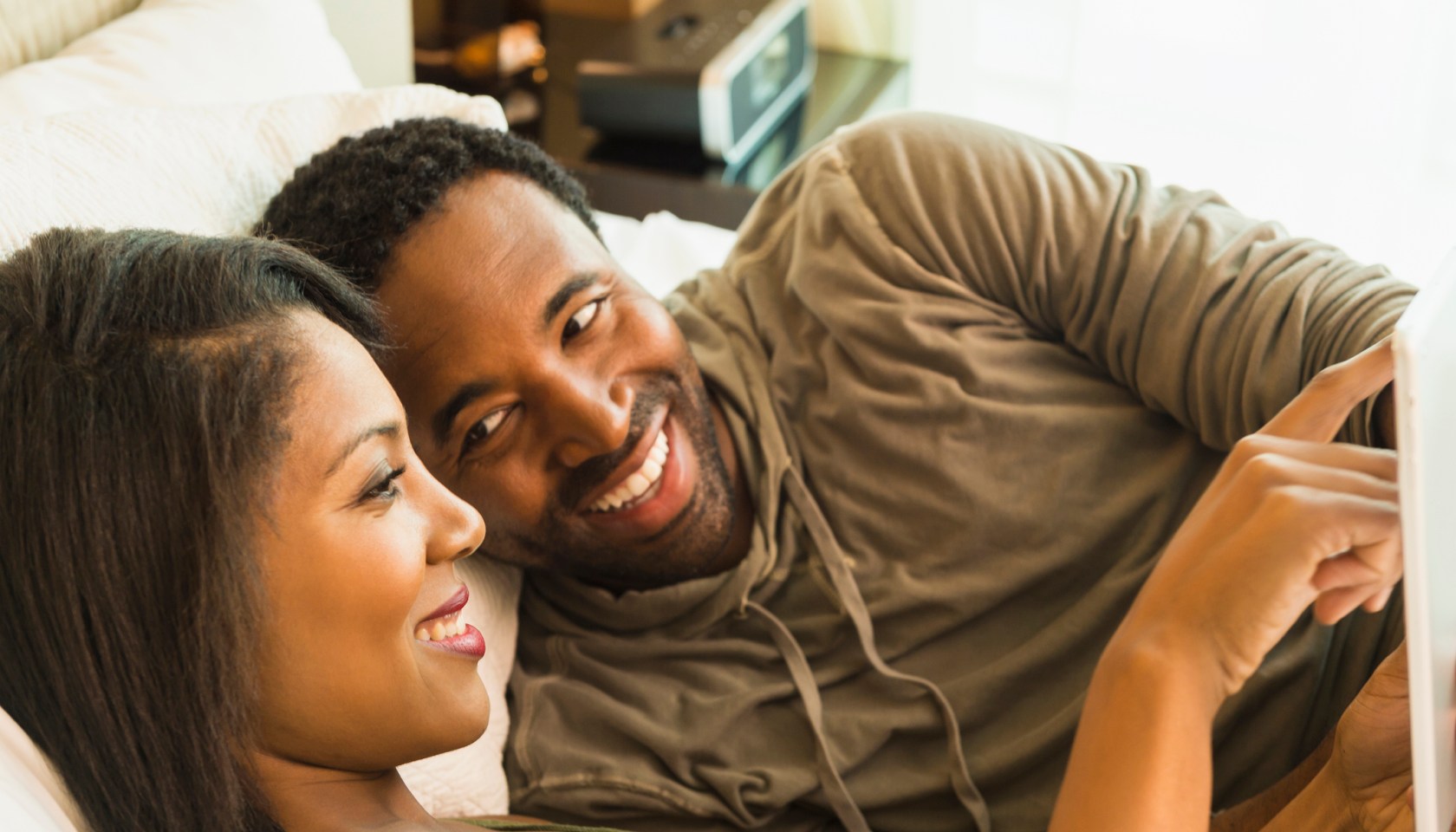 Couple using digital tablet on bed
