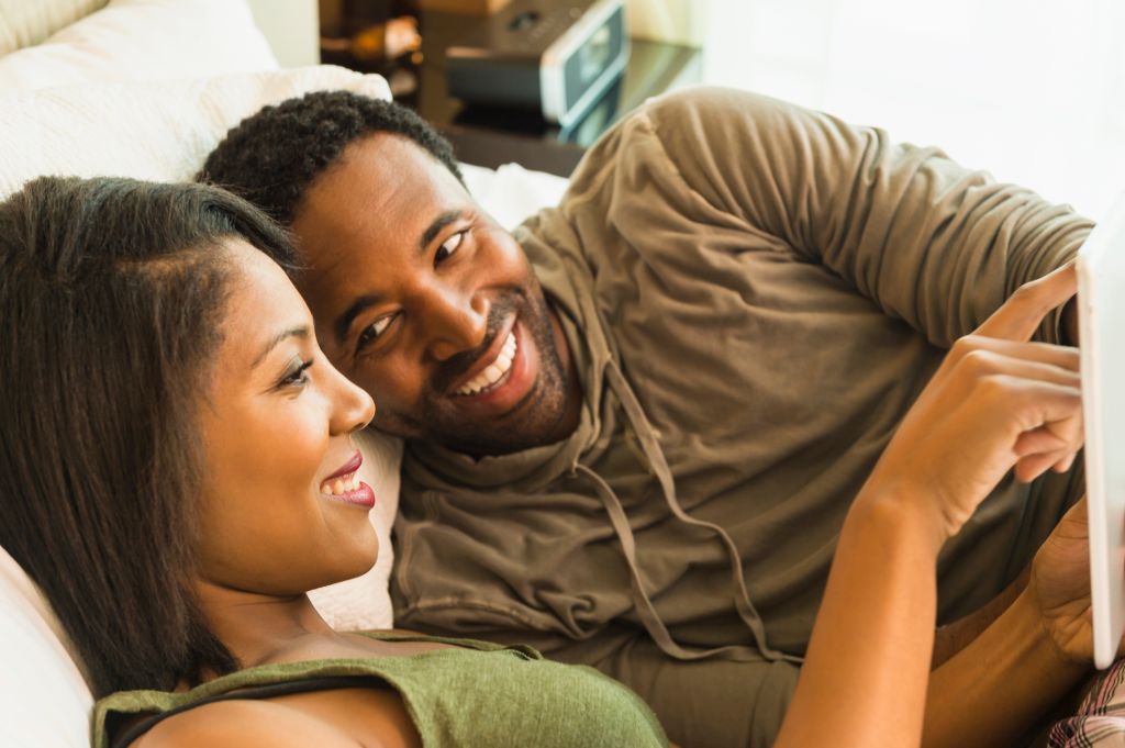 Couple using digital tablet on bed