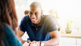 Smiling young man holding hands of woman in cafe