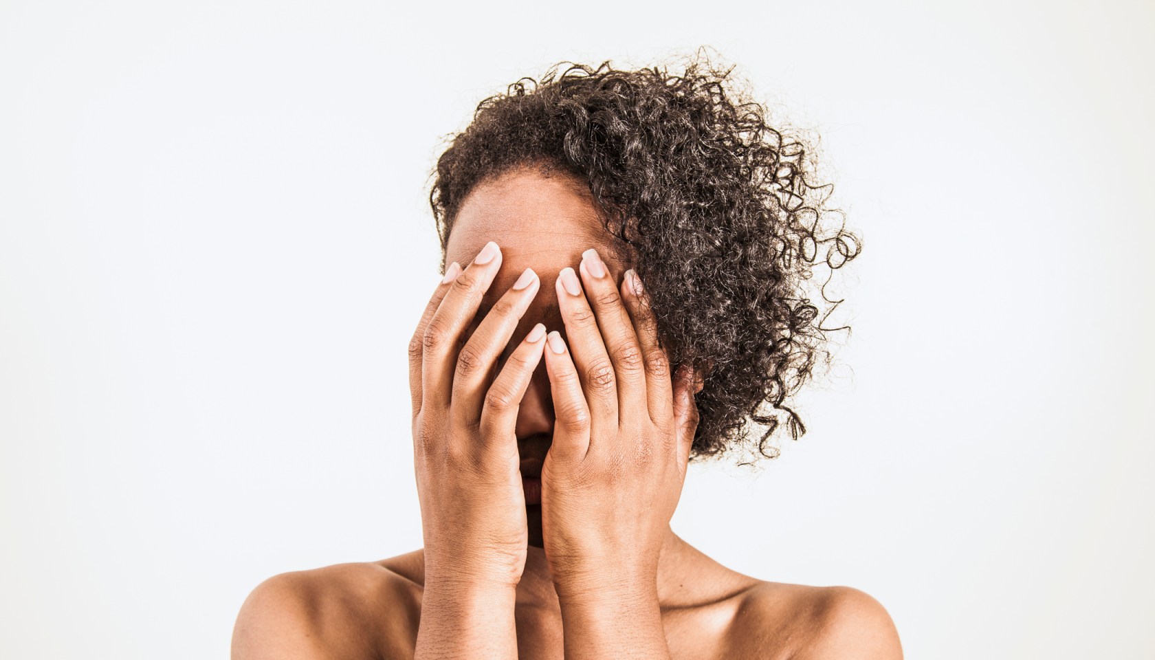 A young woman covering her face with her hands