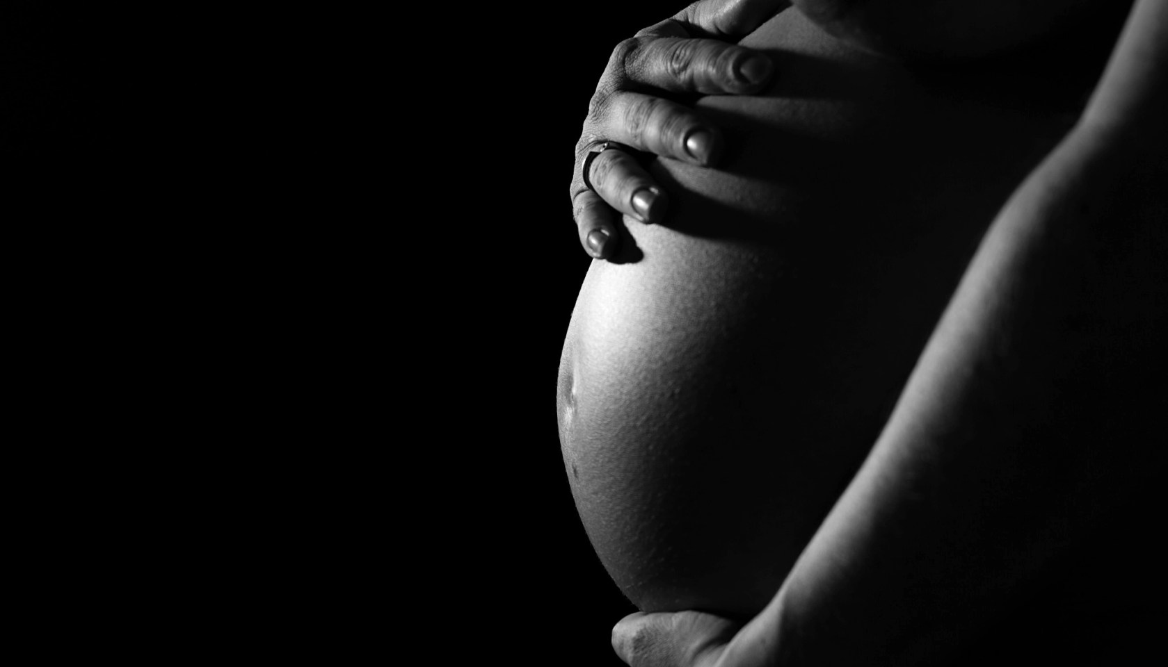 Midsection Of Pregnant Woman In Darkroom