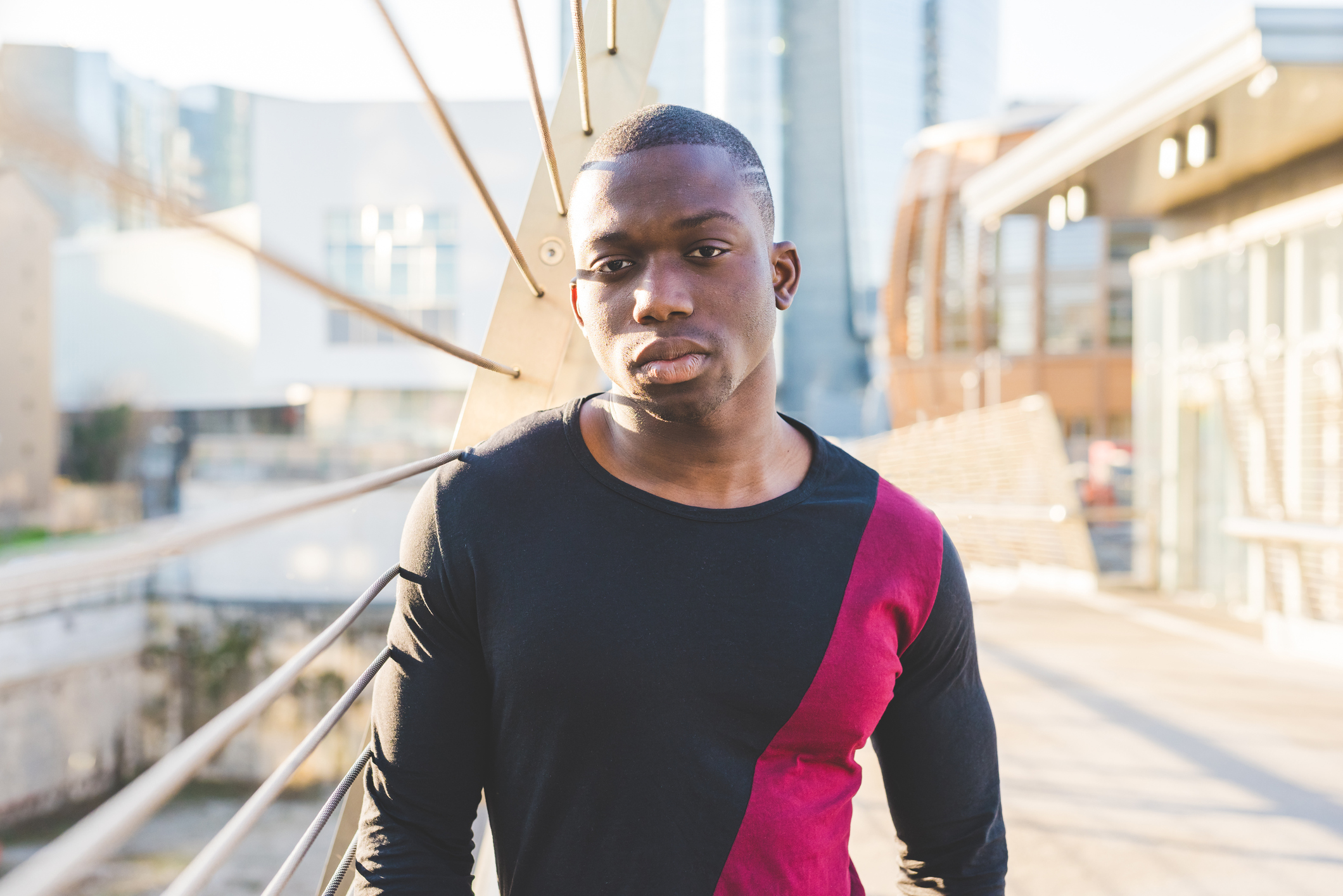 Young man standing on footbridge, pensive expression